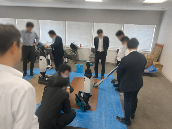床洗浄機の実演を見学する参加者