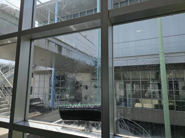 ウォーターポールのブラシで高所ガラスを洗浄している様子