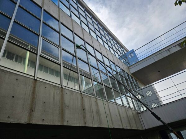 学校施設の高所ガラスをウォーターポールで清掃している様子